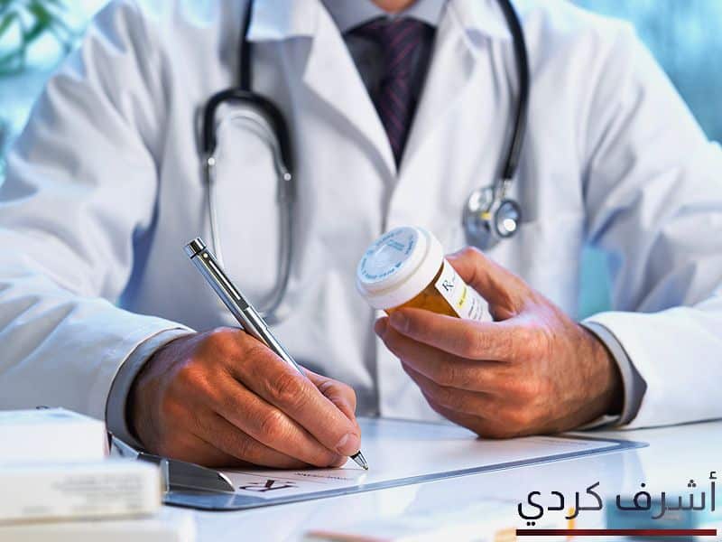 طبيب جالس يرتدي بالطو وسماعات ويحمل قلم في يد واليد الاخري يحمل بها علبة دواء